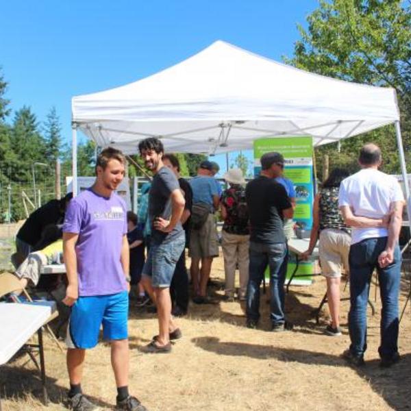 Photo link to the get involved upcoming events page. Photo showing employees and community members under a tent at a community engagement event.